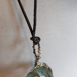 Transparent pendant in a metallic casing with a black leather cord, without a clasp